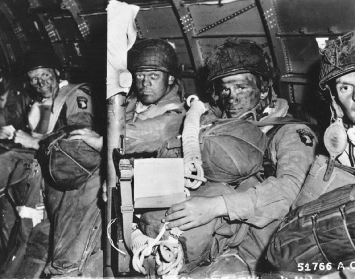 Heavily armed paratroopers of the 101st Airborne Division await the signal to stand up and hook up, then jump into Normandy 